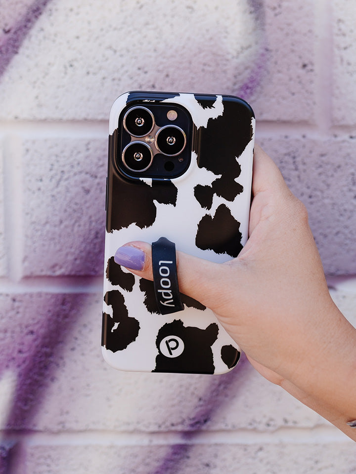 A woman holding a Cow Print Loopy Case.