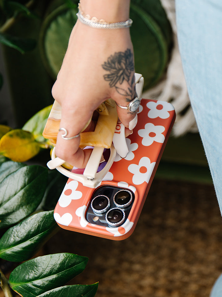 A woman holding an Auburn Daisies Loopy Case.|| feature-media