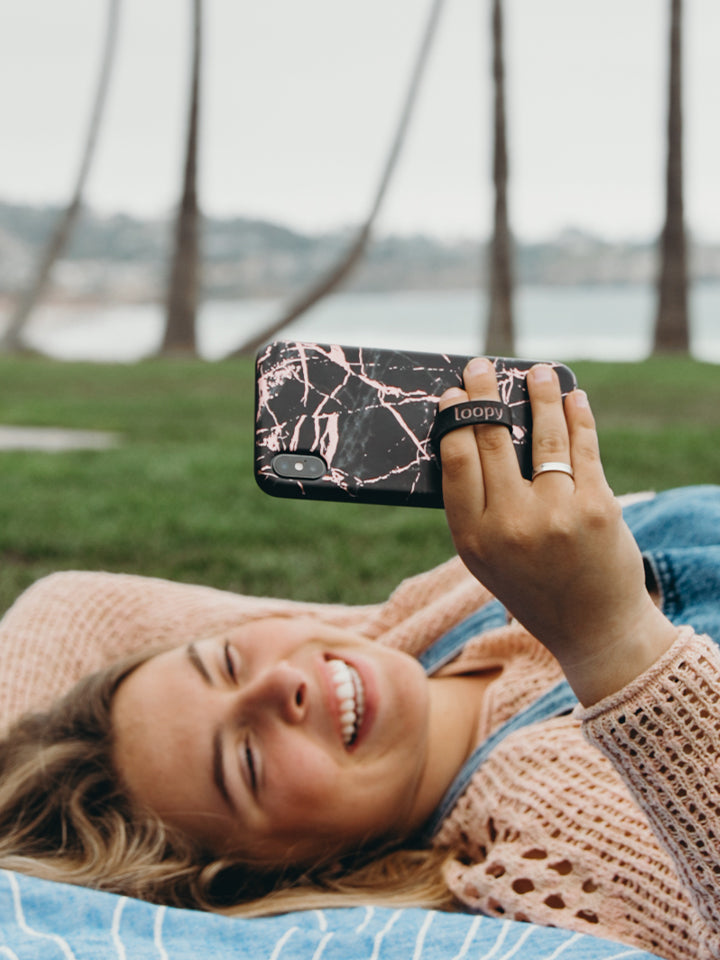 A woman holding a Black Rose Marble Metallic Loopy Case. || feature-media