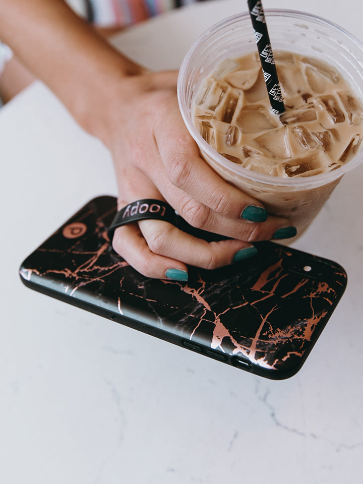 A woman holding a Black Rose Marble Metallic Loopy Case. || feature-media