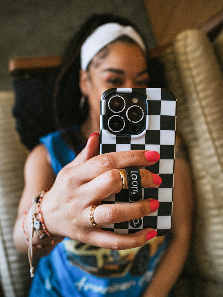 A woman taking a selfie while holding a Black and White Checkered Loopy Case. || feature-media