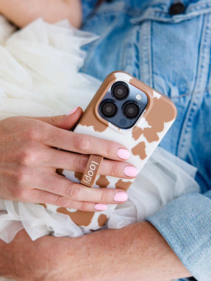 A woman holding a Brown Cow Print Loopy Case.|| feature-media