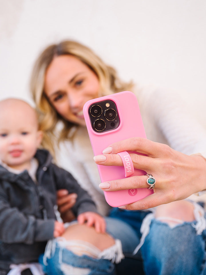 A woman taking a selfie while holding a Bubblegum Pink Loopy Case.|| feature-media