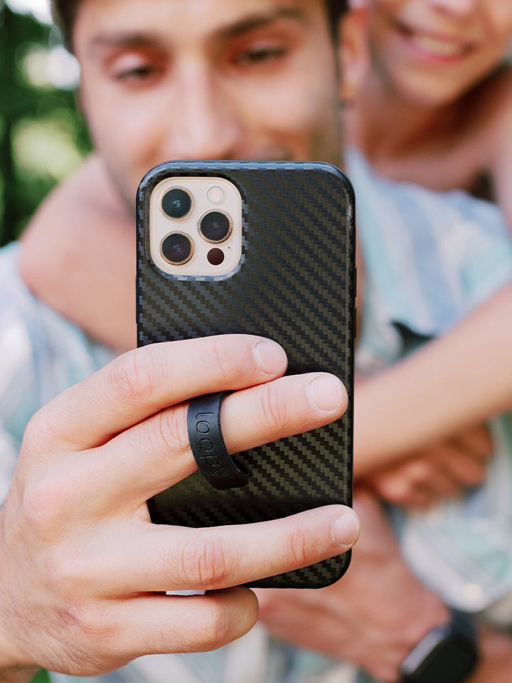 A man taking a selfie while holding a Carbon Loopy Case.|| feature-media