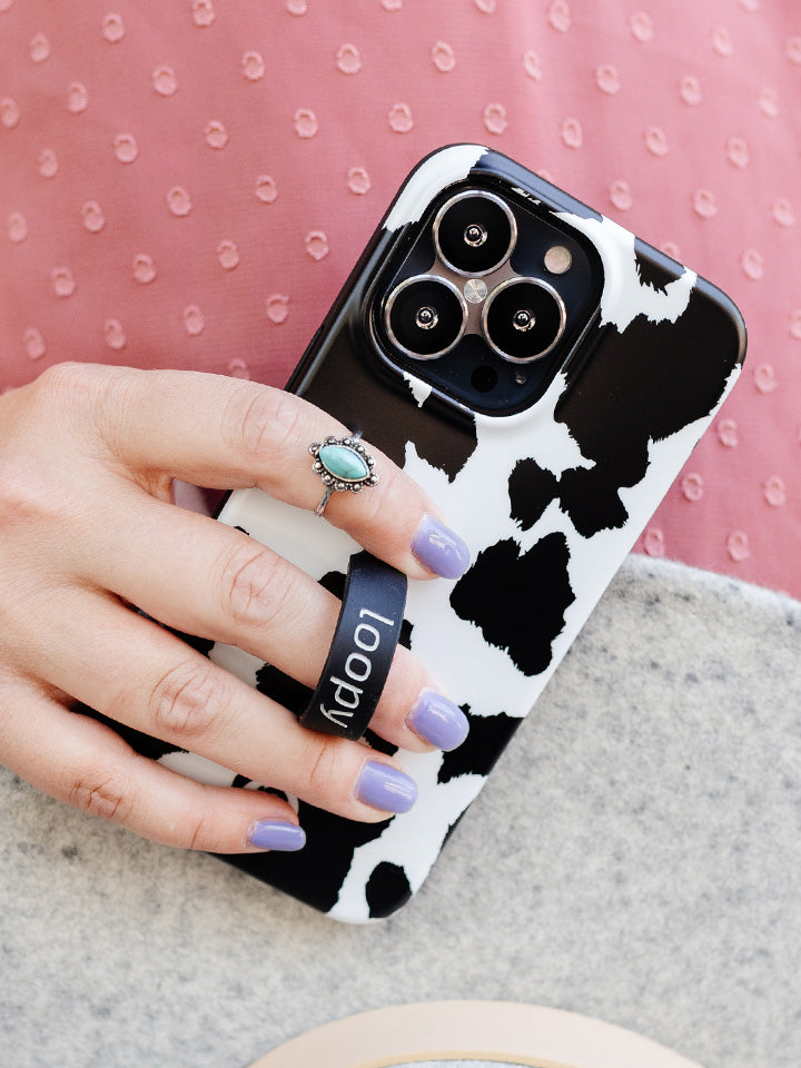 A woman holding a Cow Print Loopy Case.|| feature-media