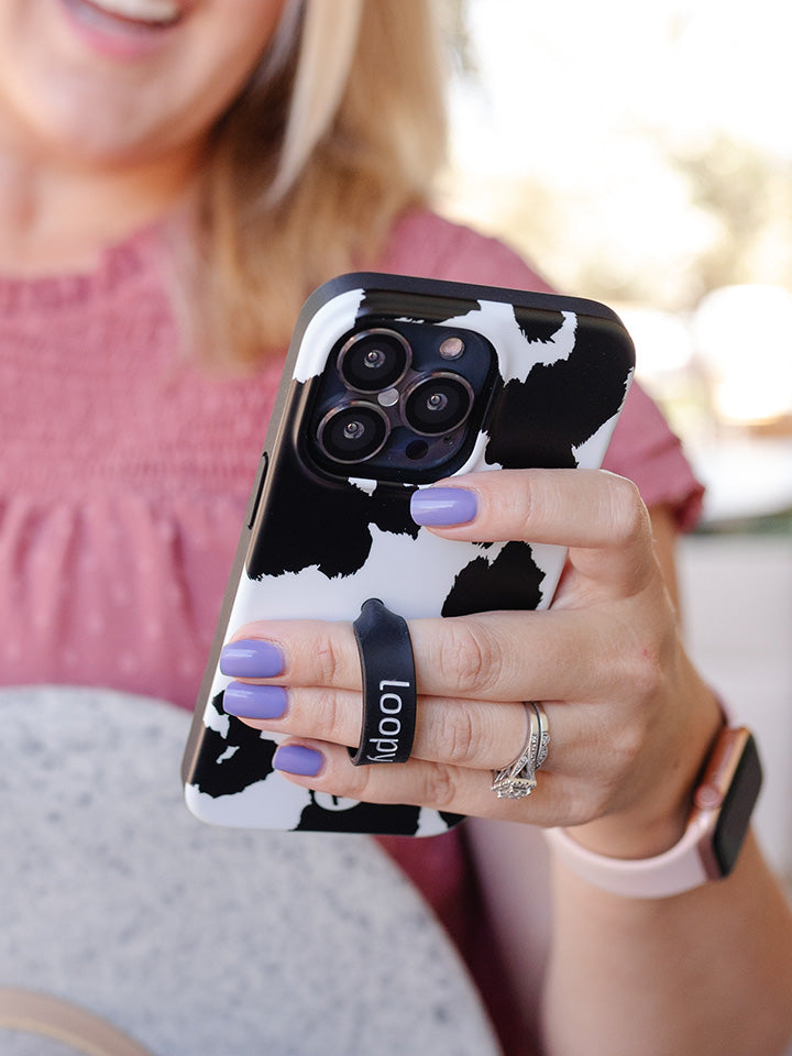 A woman holding a Cow Print Loopy Case.|| feature-media