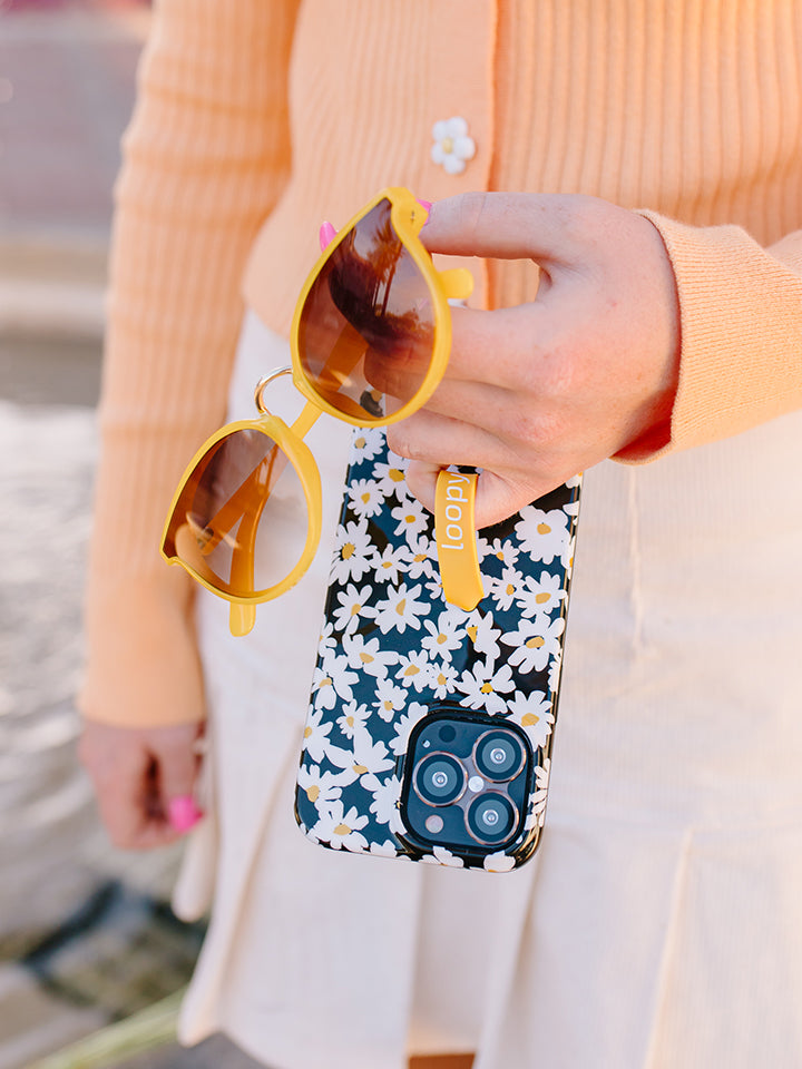 A woman holding a Daisies Loopy Case. || feature-media