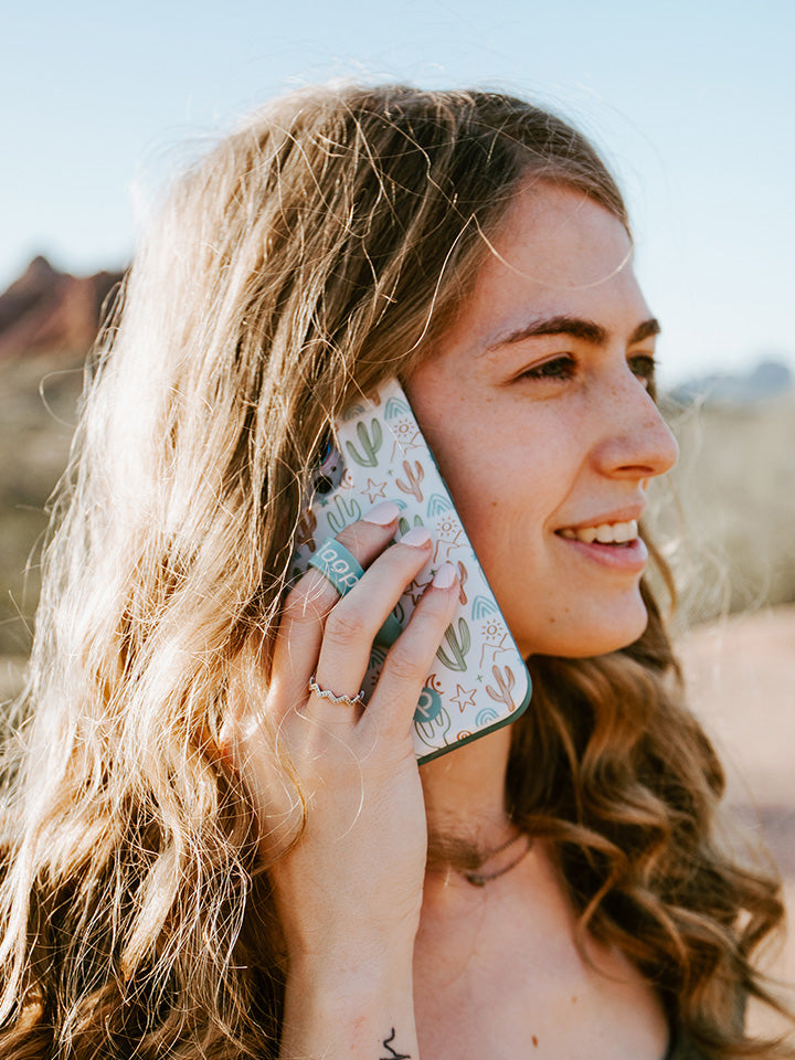 A woman talking on the phone while holding a Desert Bliss Loopy Case.|| feature-media