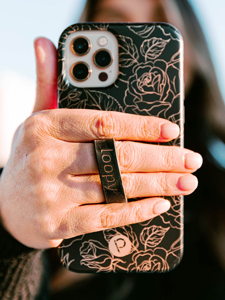 A woman holding an Enchanted Rose Loopy Case. || feature-media