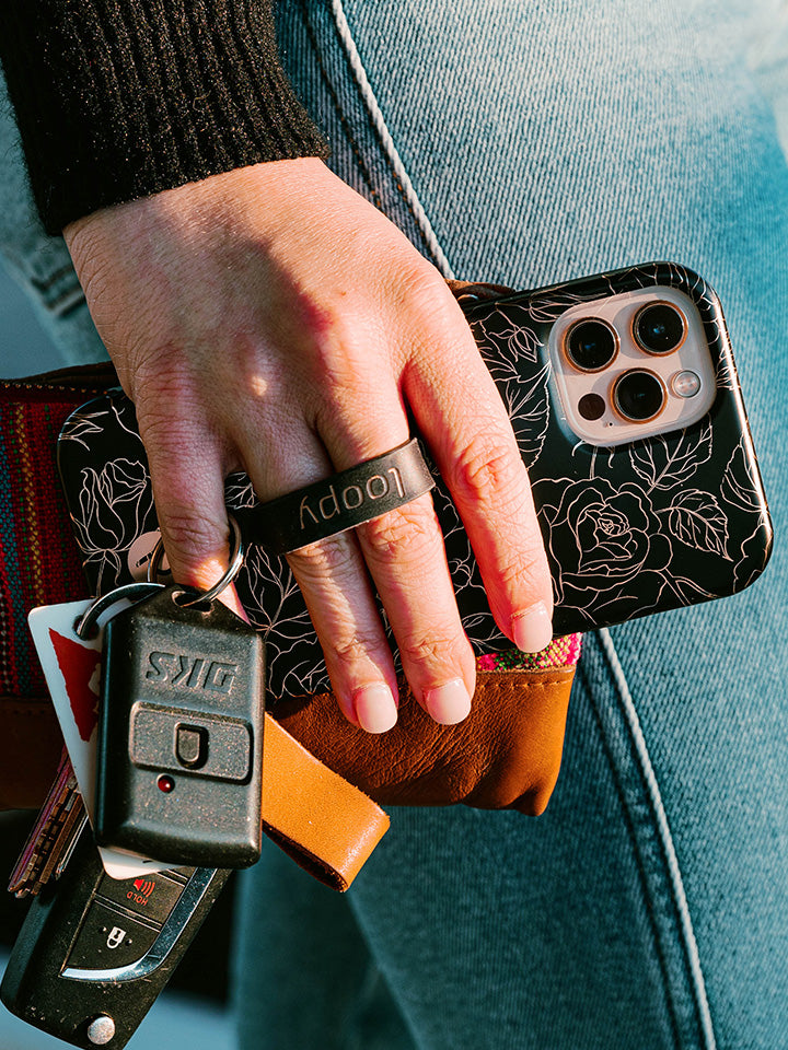 A woman holding an Enchanted Rose Loopy Case. || feature-media