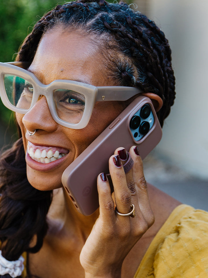 A woman talking on the phone while holding an Espresso Loopy Case. || feature-media