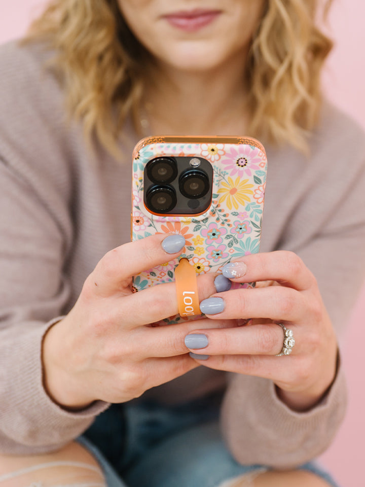 A woman holding a Floral Burst Loopy Case.|| feature-media