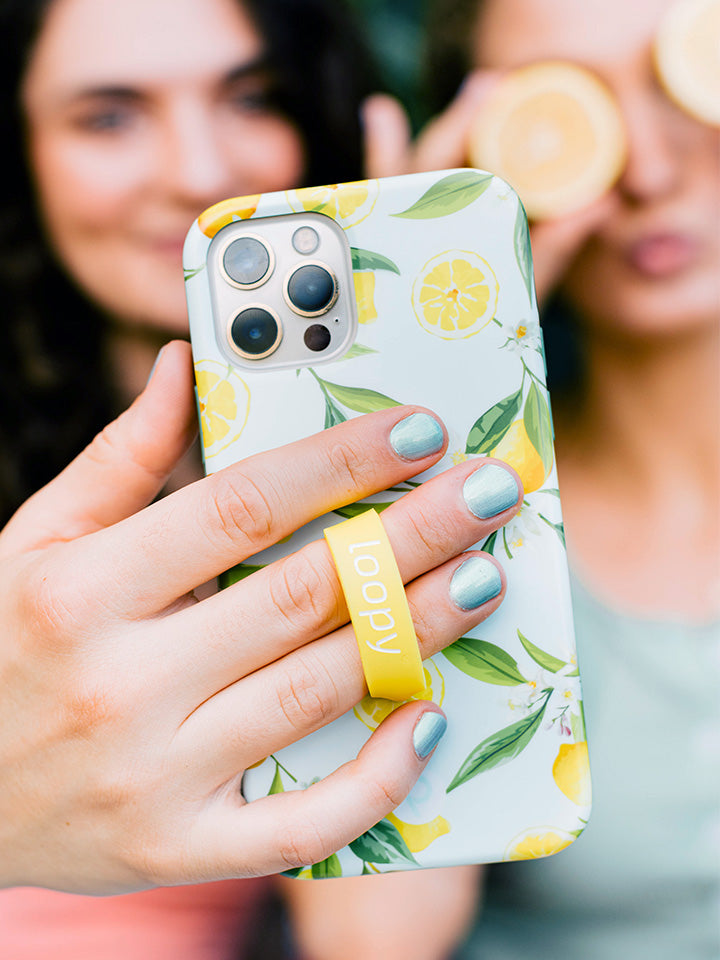 A woman taking a selfie while holding a Lemons Loopy Case. || feature-media