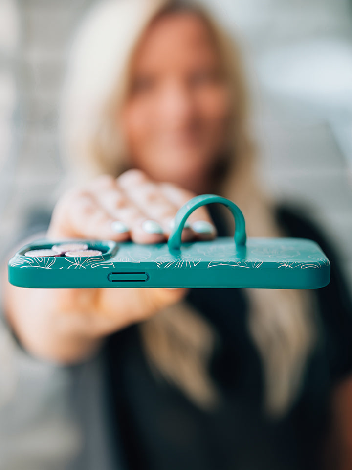 A woman holding a Metallic Monstera Loopy Case. || feature-media