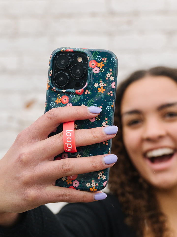 A woman taking a selfie while holding a Midnight Meadow Loopy Case. || feature-media