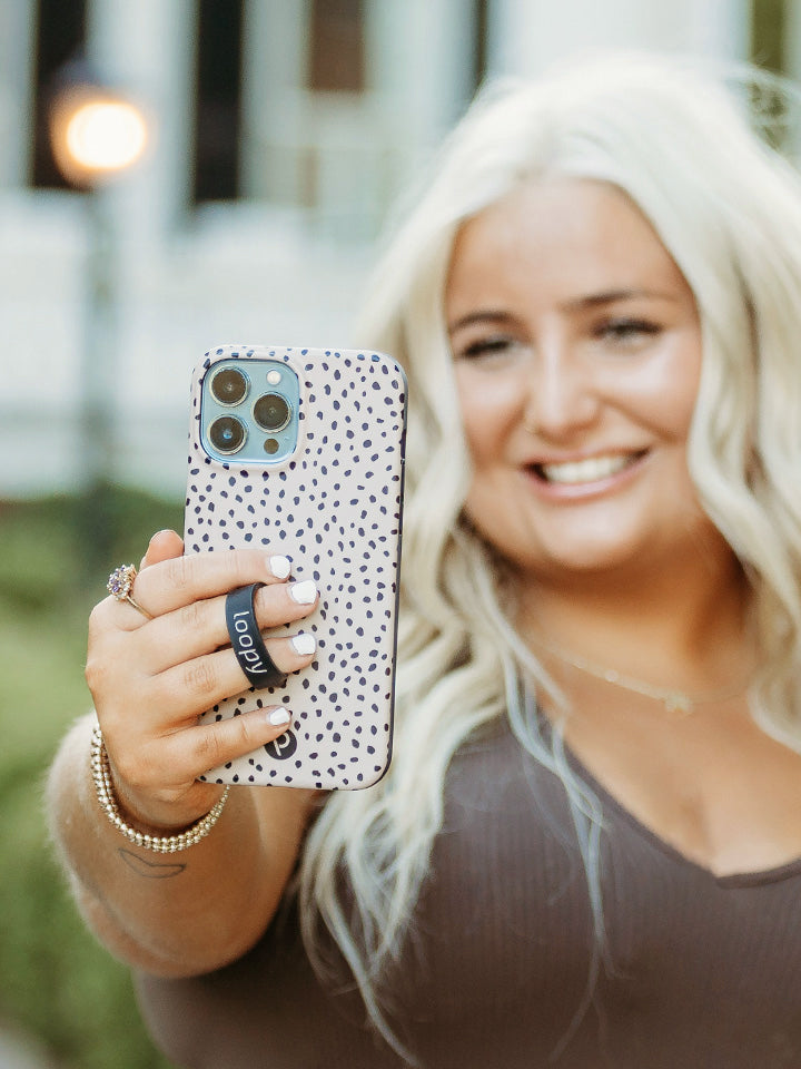 A woman taking a selfie while holding a Mocha Dots Loopy Case.|| feature-media