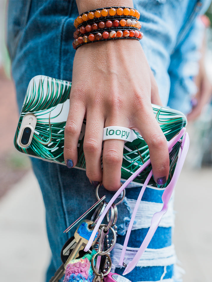 A woman holding a Monstera Loopy Case. || feature-media