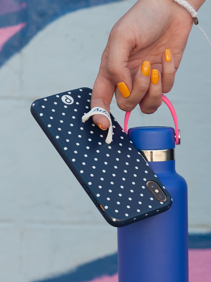 A woman holding a Navy Polka Dot Loopy Case. || feature-media