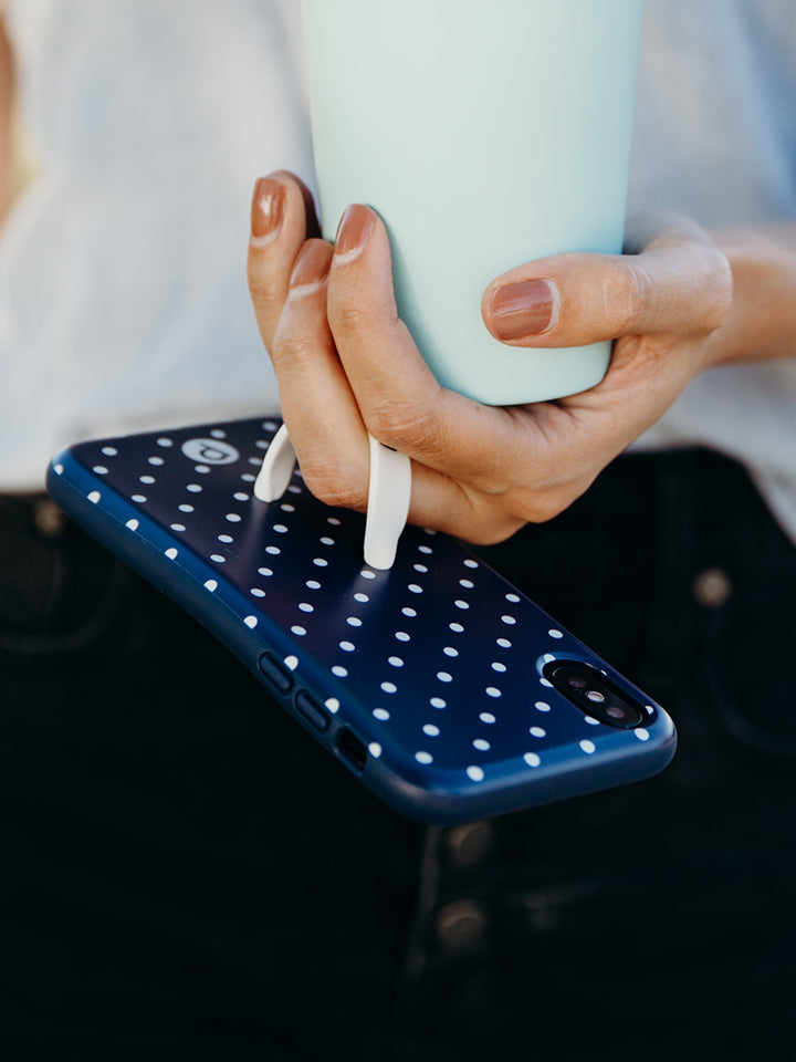 A woman holding a Navy Polka Dot Loopy Case. || feature-media