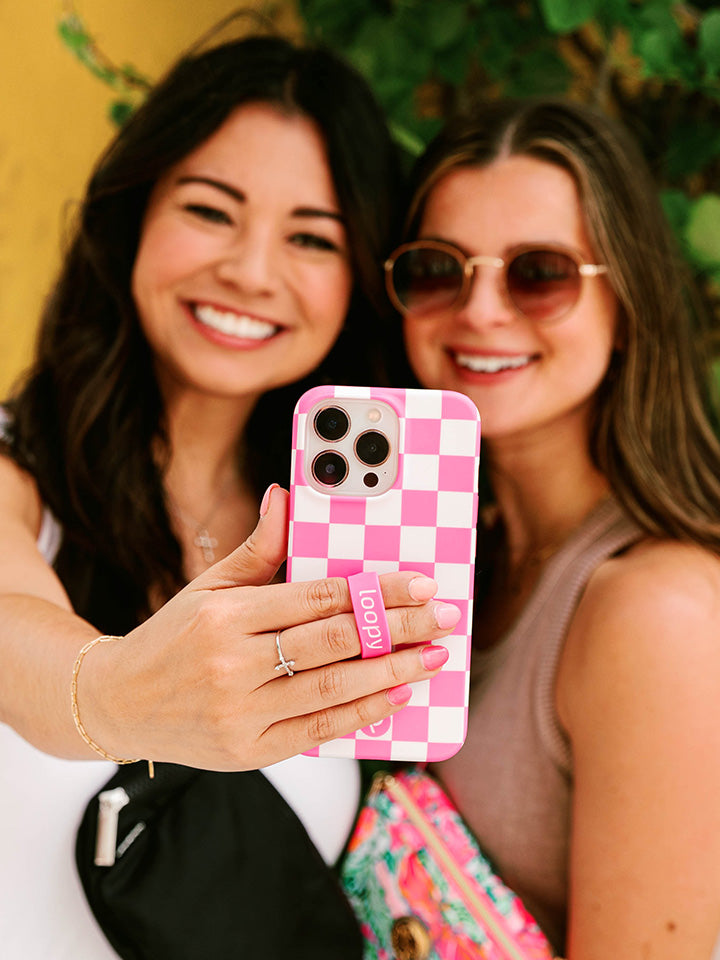 A woman taking a selfie while holding a Pink Checkered Loopy Case.|| feature-media