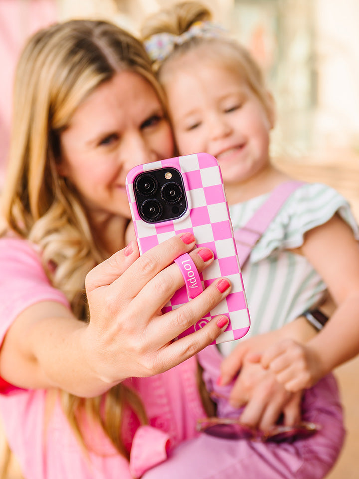 A woman taking a selfie while holding a Pink Checkered Loopy Case.|| feature-media