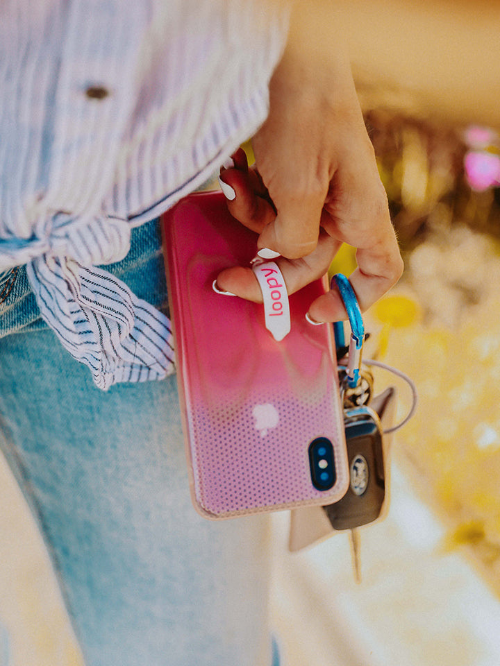 A woman holding a Pink Ombre Loopy Case. || feature-media