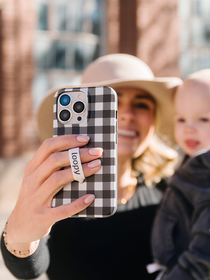 A woman taking a selfie while holding a Plaid Loopy Case.|| feature-media