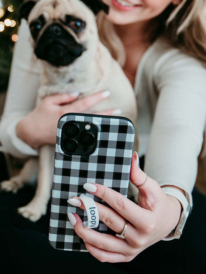 A woman taking a selfie while holding a Plaid Loopy Case.|| feature-media