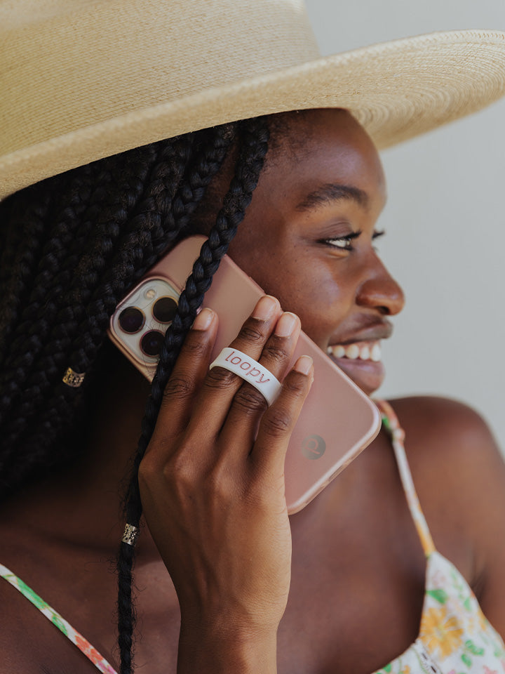 A woman talking on the phone while holding a Rose Gold Loopy Case.|| feature-media