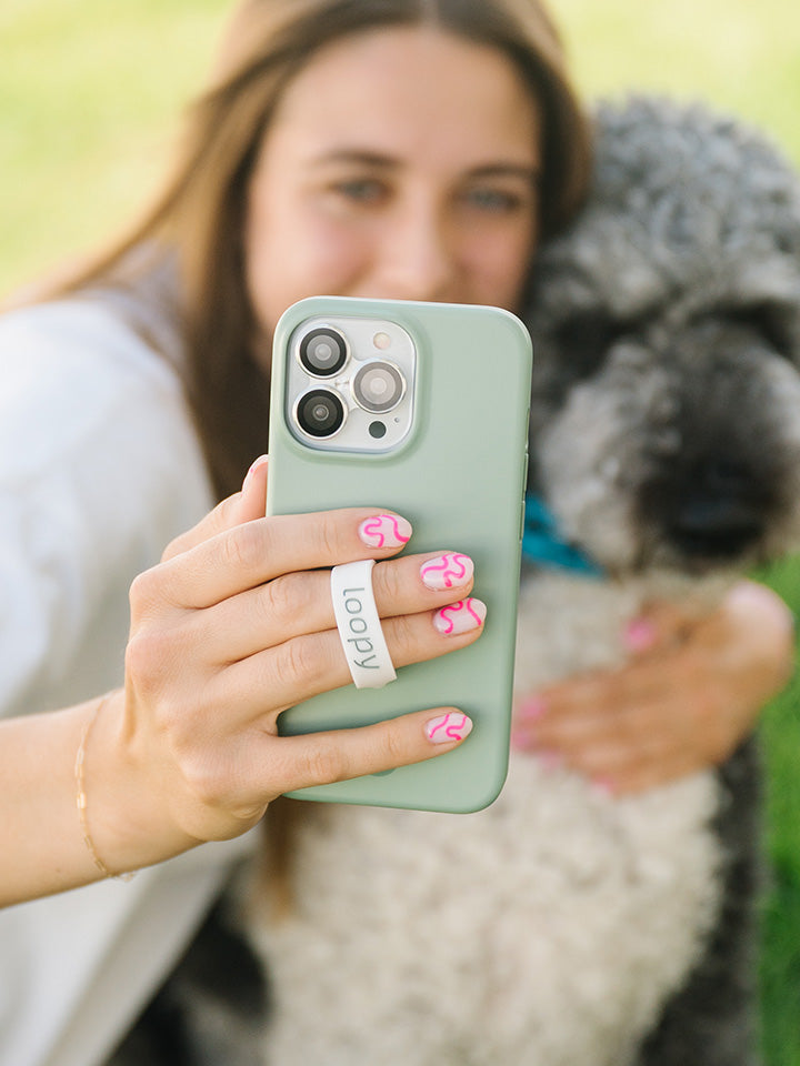 A woman taking a selfie while holding a Sage Loopy Case.|| feature-media