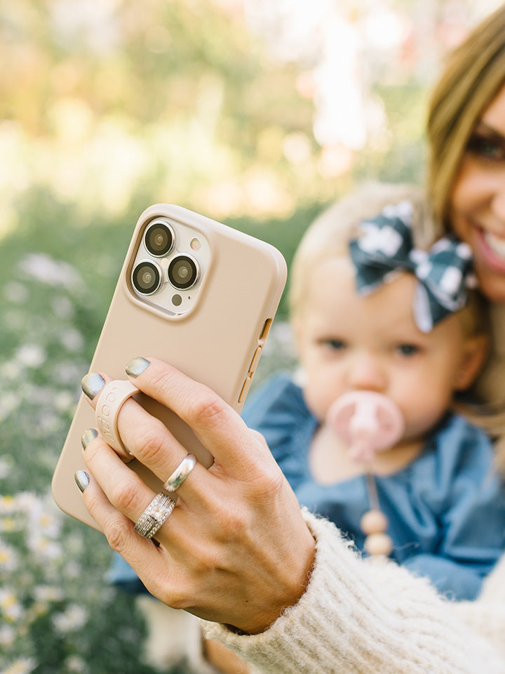 A woman taking a selfie while holding a Sandstone Loopy Case. || feature-media