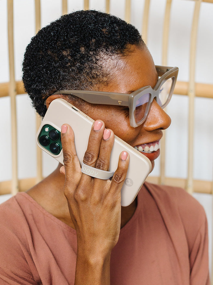 A woman talking on the phone while holding a Sandstone Loopy Case. || feature-media