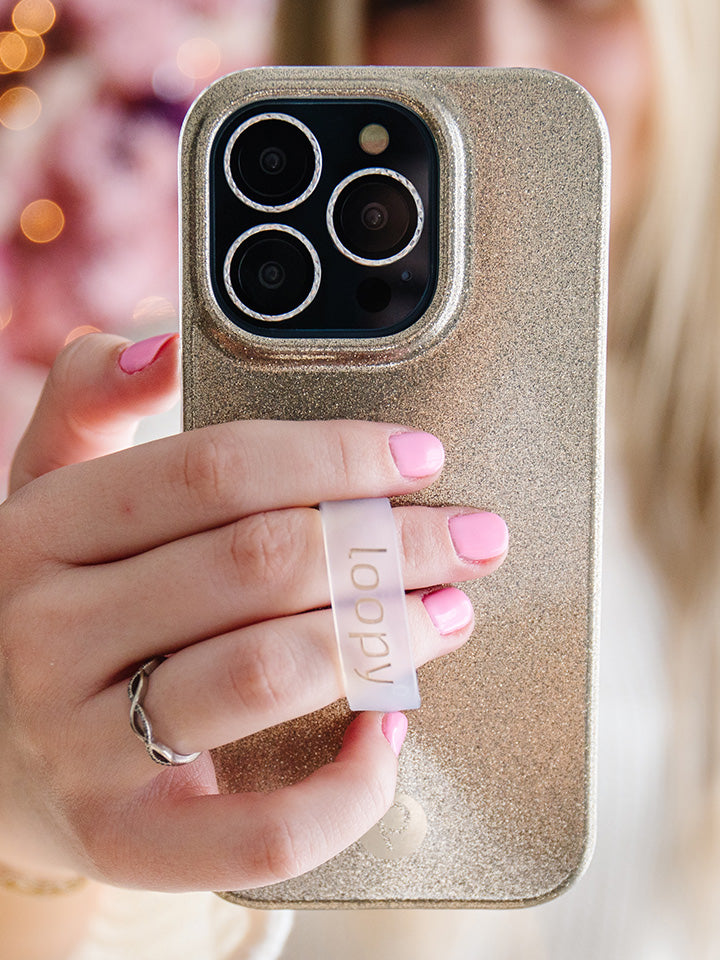 A woman holding a Champagne Sparkle Loopy Case. || feature-media