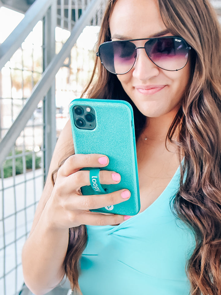 A woman holding a Sparkle Turquoise Loopy Case. || feature-media