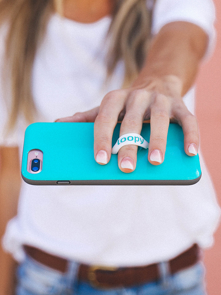 A woman holding a Turquoise Loopy Case. || feature-media