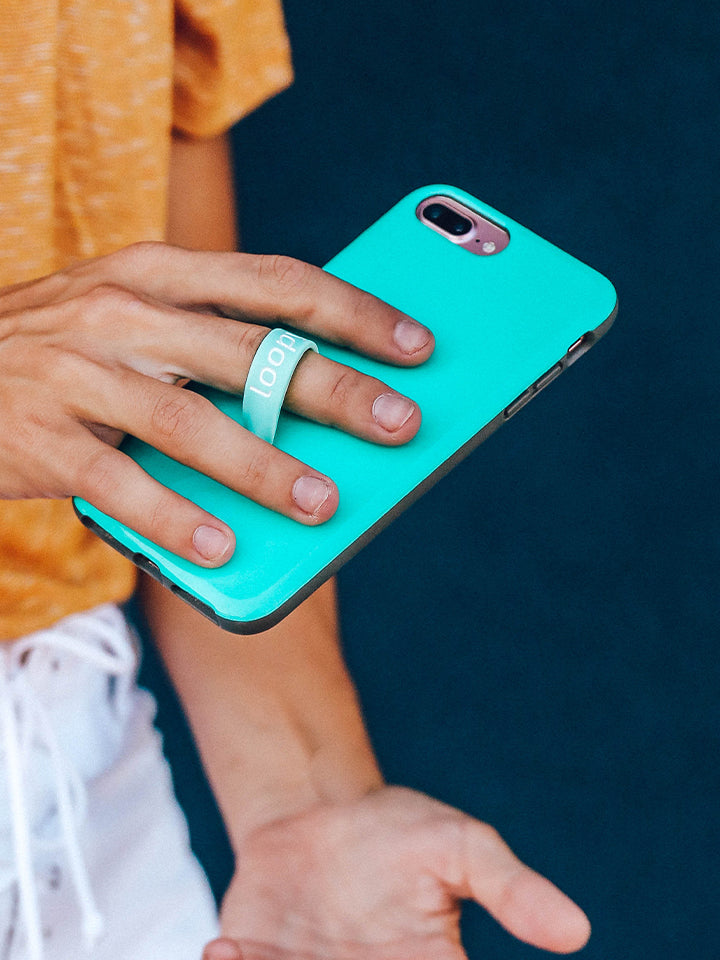 A woman holding a Turquoise Loopy Case. || feature-media