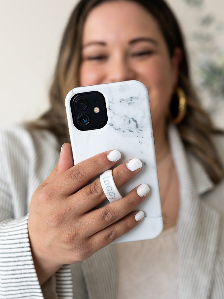 A woman holding a White Marble Loopy Case. || feature-media