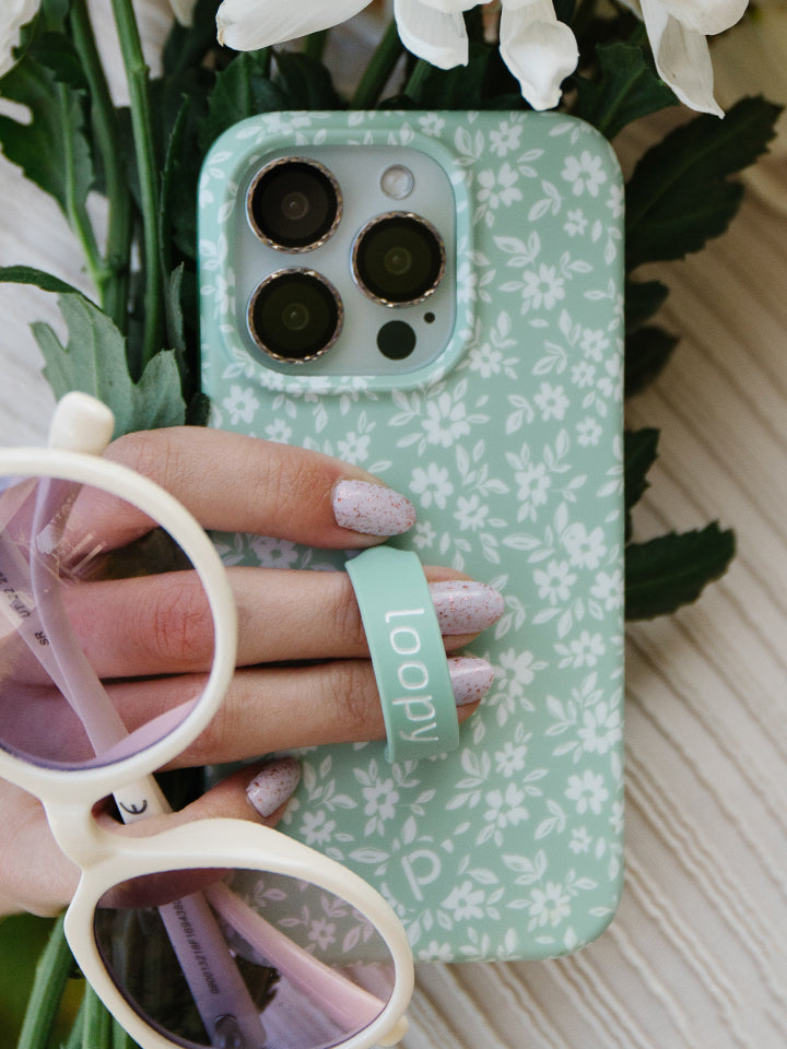 A woman holding a Sage Floral Loopy Case. || feature-media