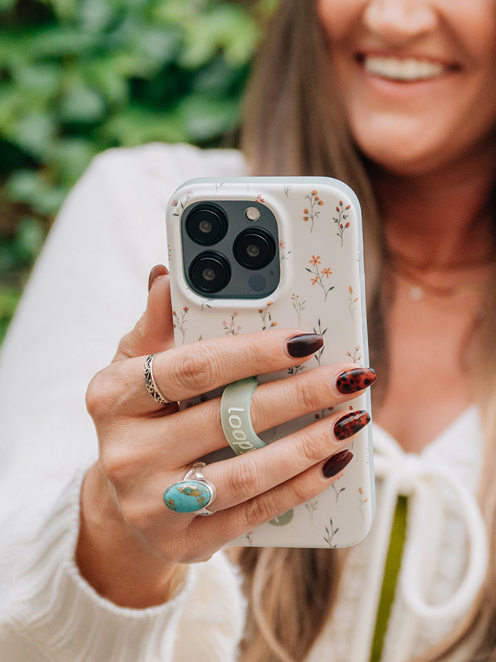 A woman holding a Whispering Wildflowers Loopy Case. || feature-media