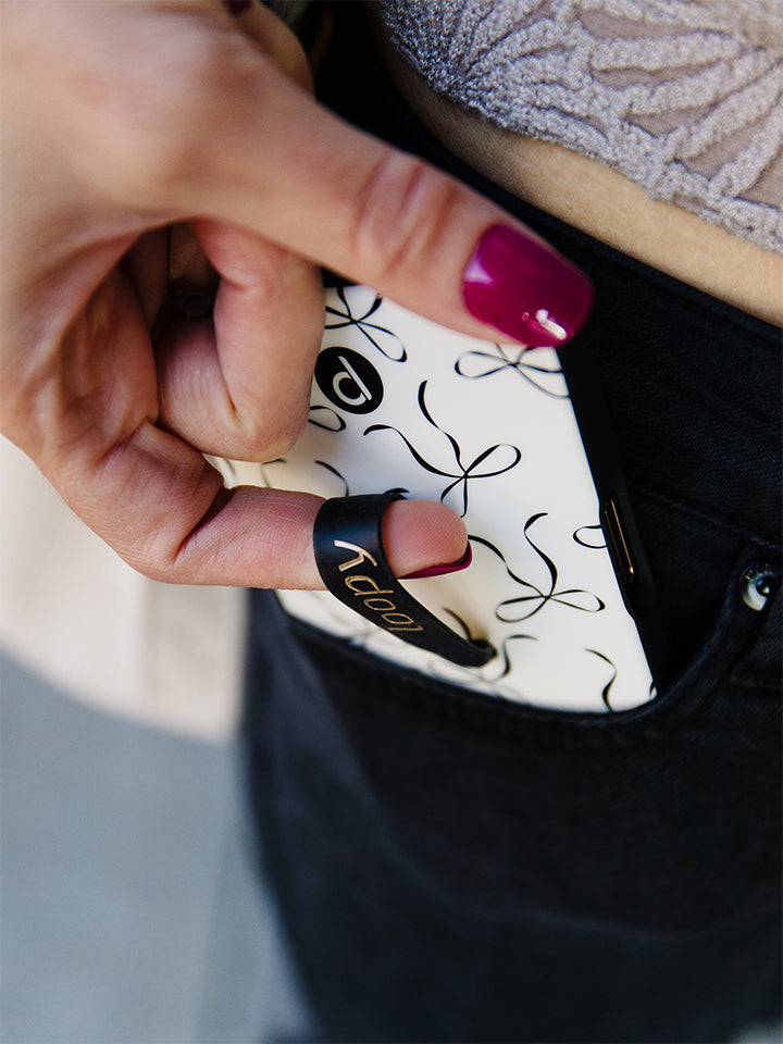 A woman putting a Loopy Case that has a Thin Loop on it in her front jeans pocket. || feature-media