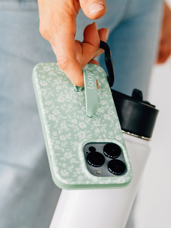 A woman holding a Sage Floral Loopy Case. || feature-media